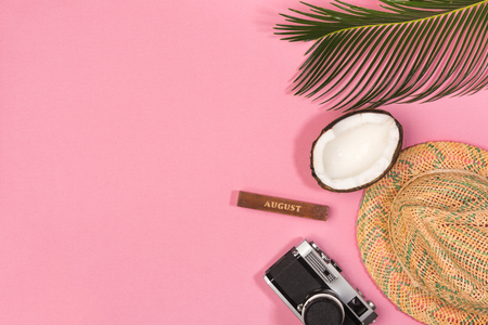 Summer vacation concept. Coconut, retro photo camera, hat and green palm leaves on pink background, flat lay. space for textの写真素材