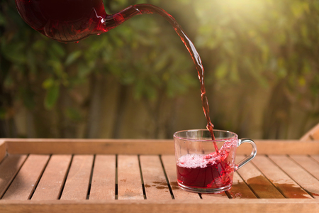 Pouring tea from a teapot into a cup on a blurred background of natureの写真素材