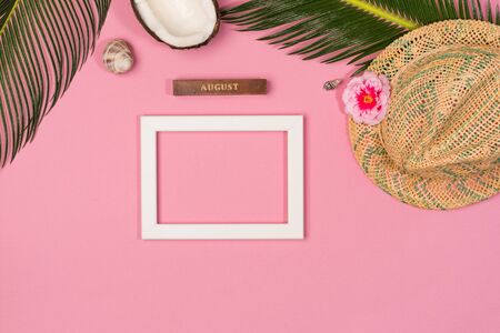 Summer composition with photo frame, green leaves, hat and coconut on a pink pastel background. Artwork mockup with copy spaceの写真素材