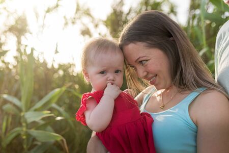 Happy family outdoor. Parents hold child on hands and rejoice. They are happy together