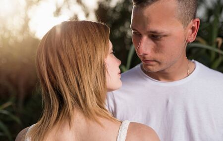 Close up of a smiling young couple embracing at the park, relaxing