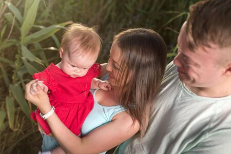 Portrait of happy young couple with baby girl in summer parkの写真素材