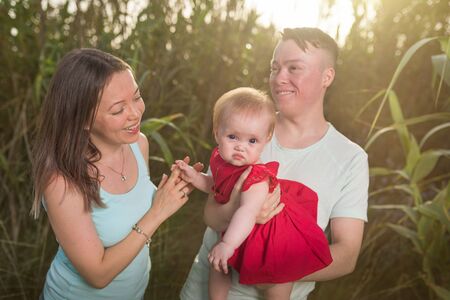 Happy family in the park evening light. The lights of a sun. Mom, dad and baby happy walk at sunset....