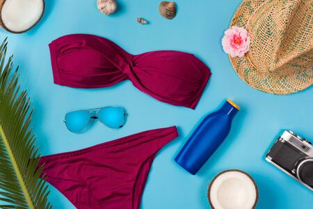 Beach theme on the blue background. Sunglasses, hat, sunscreen, swimsuit, on the blue background. Top view.の写真素材