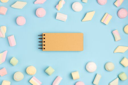 Blue paper background with marshmallow and notepad. Place for your text. Cozy sweet backgroundの写真素材