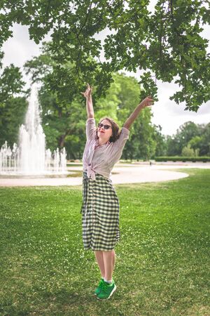 Happiness concept - happy woman having fun on city park during summerの写真素材