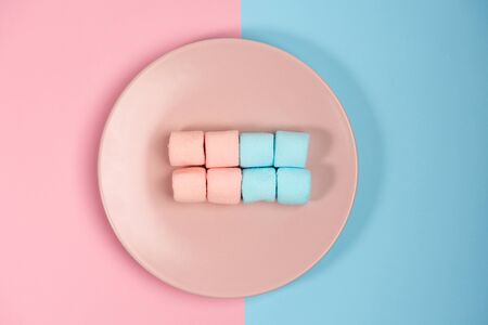 Pink plate with marshmallow, isolated on blue and pink, background. Top view.の写真素材