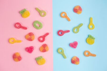 Multicolored gummy candies on pink and blue backgrounds. Top view.