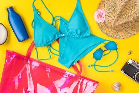 Beach theme on the yellow background. Beach bag, hat, coconut, swimsuit, camera, on the yellow background. Top view.の写真素材