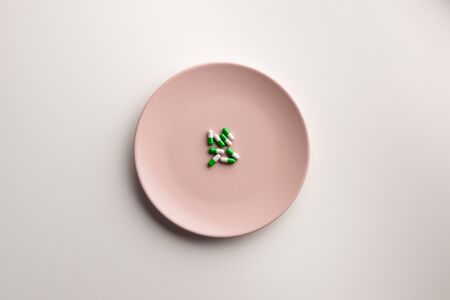Medical capsules on a plate, isolated on white background. Flat lay.の写真素材