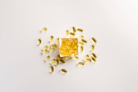 Bowl with fish oil capsules, isolated on white background. Flat lay.の写真素材