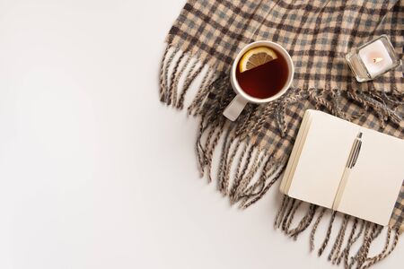 Autumn, cozy concept. Cup of tea, warm scarf, notebook, isolated on white background. Flat lay.の写真素材