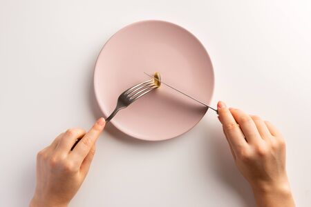 Female hands holding fork and knife. Plate with fish oil capsule. Flat lay.の写真素材
