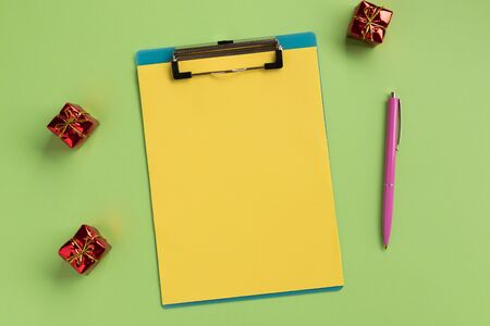 Christmas or New Year planning concept. Clipboard with yellow sheet and pen, on green background. Flat lay, top view, copy space.の写真素材