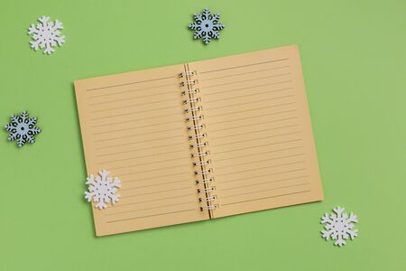 Open notebook and snowflakes, on green background. Flat lay, top view, copy space.の写真素材