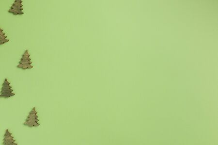 Small wooden christmas trees on green background. Christmas, winter concept. Flat lay, top view, copy space.の写真素材