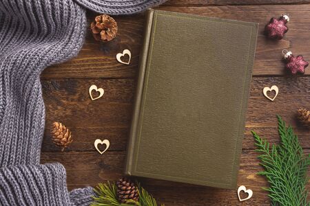 Winter, cozy composition. Warm plaid, book and christmas decoration, on wooden background. Flat lay, top view, copy space.の写真素材
