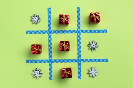 Tic tac toe game with christmas toys, isolated on green background. Christmas, winter concept. Flat lay, top view.の写真素材