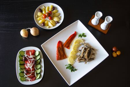 Greek traditional fried anchovies gavros tiganitos heap with a sliced lemon on a plate, greek salad...