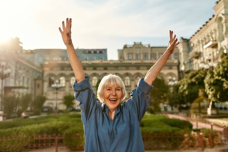 Age is no barrier. Portrait of happy and beautiful senior woman raising hands up and smiling while standing outdoors on a sunny day. Old age. Happinessの写真素材