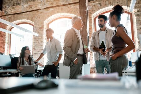 Office life. Group of modern people talking with each other and discussing business ideas while standing in the creative office. Teamworkの写真素材