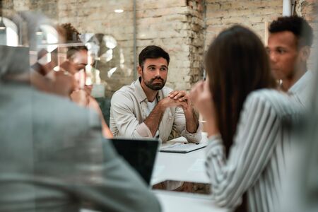 Brainstorming. Business people discussing something and working together while sitting at the office table behind the glass wall in the modern officeの写真素材