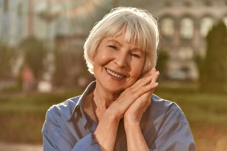 Age is just a number. Portrait of happy and beautiful senior woman looking at camera and smiling while standing outdoors on a sunny day. Old age. Happinessの写真素材