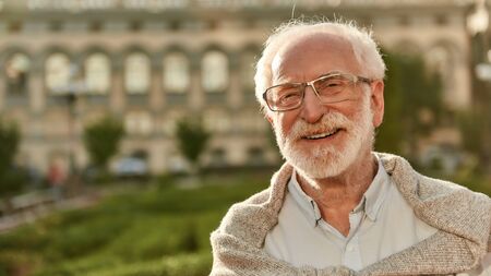 It's never too late. Portrait of happy and handsome bearded senior man in glasses looking at camera and smiling while spending time outdoors on a sunny day. Old age. Happinessの写真素材
