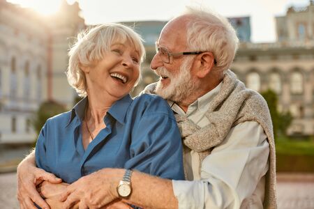Feeling happy with you. Cheerful senior couple in casual clothing embracing each other and laughing while standing together outdoors. Love concept. Familyの写真素材