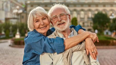 I love my husband. Portrait of cheerful senior couple in casual clothing embracing each other and looking at camera with smile while standing together outdoors. Love concept. Familyの写真素材