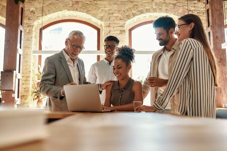 We have great results. Multicultural team looking at the laptop and discussing something while working together in the modern office. Teamwork. Office lifeの写真素材