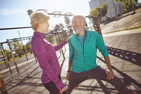 Happy and healthy. Smiling mature family couple in sportswear doing gymnastics together at outdoor gym. Man and woman doing stretching exercises outdoorsの写真素材