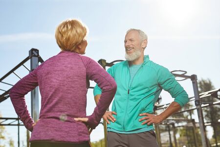 Morning exercises. Happy senior family couple in sportswear doing gymnastics together at outdoor gym. Man and woman doing sport outdoorsの写真素材