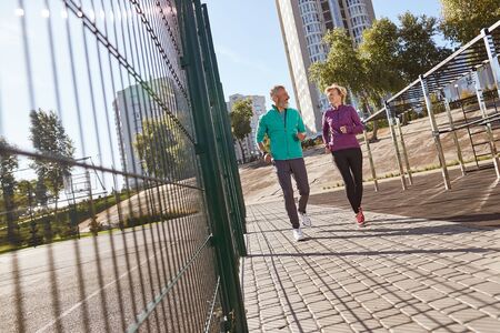 Morning jog. Active mature family couple in sportswear running together at the stadium in the early morning. Full length. Beautiful seniour couple doing sport outdoorsの写真素材