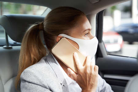 Business during coronavirus. Business woman wearing protective face mask talking by mobile phone...