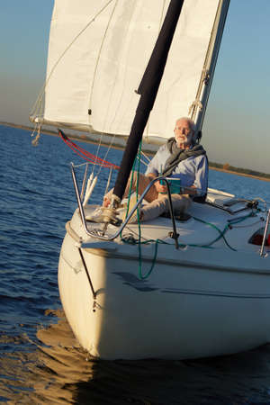Vertical shot of relaxed retired man enjoying amazing view and relaxing, reading book while sitting...