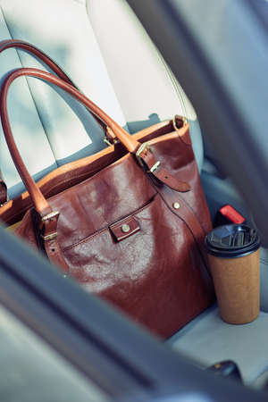 Day starting with coffee, close up shot of a handbag and cup of coffee on the passenger car seatの写真素材