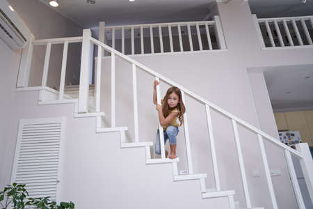Little cute girl playing on stairs at homeの写真素材