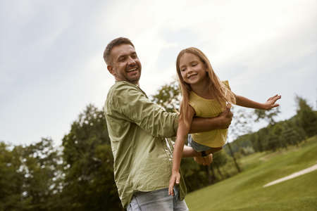 Happy father and his little daughter having fun in park on a warm summer day, they a smiling and feeling so happy while spending time togetherの写真素材