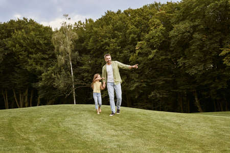 Spending time with dad. Young father and his cute little daughter walking in the park on a warm summer dayの写真素材