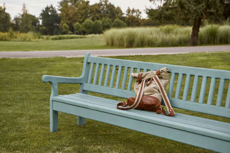 Casual backpack on the wooden bench outdoors with green trees and grass on the backgroundの写真素材