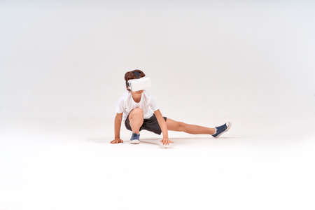 Future of the sport. Full-length shot of teenage boy wearing virtual reality or 3d glasses exercising isolated over grey background, studio shotの写真素材