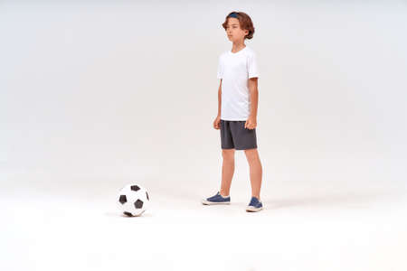 Young soccer player. Full-length shot of a teenage boy playing away while playing football isolated over grey backgroundの写真素材