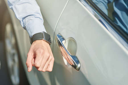 Close up shot of a male hand with smartwatch, man going to open the car while standing outdoorsの写真素材