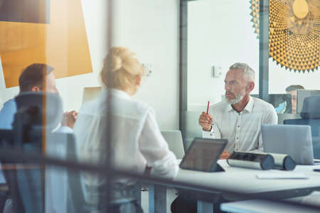 Business people sitting at desk and discussing new contract while working together in the modern office or coworking spaceの写真素材