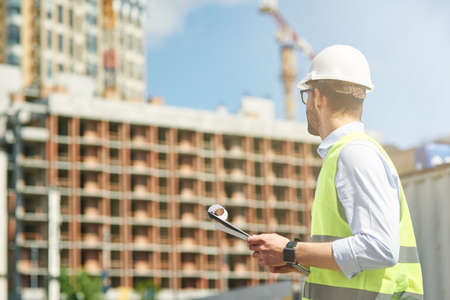 Young civil engineer wearing helmet inspecting building site, engineering and architecture conceptの写真素材