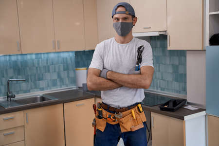 Young caucasian repairman in face mask working with furnitureの写真素材
