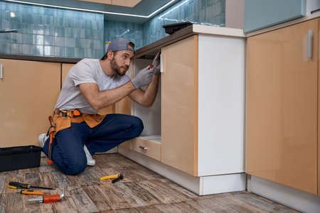 Young caucasian home master installing kitchen furnitureの写真素材