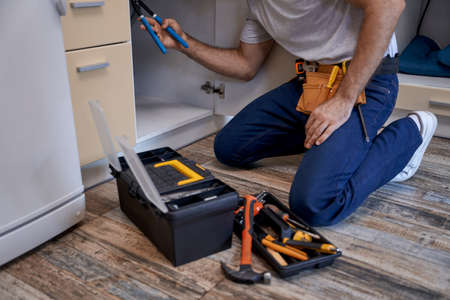 Young worker fixing tubes under kitchen sinkの写真素材