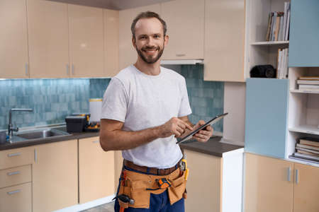 Smiling young caucasian male worker with tablet during work in kitchenの写真素材